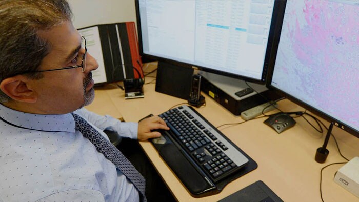 un hombre sentado en un escritorio con dos monitores de computadora